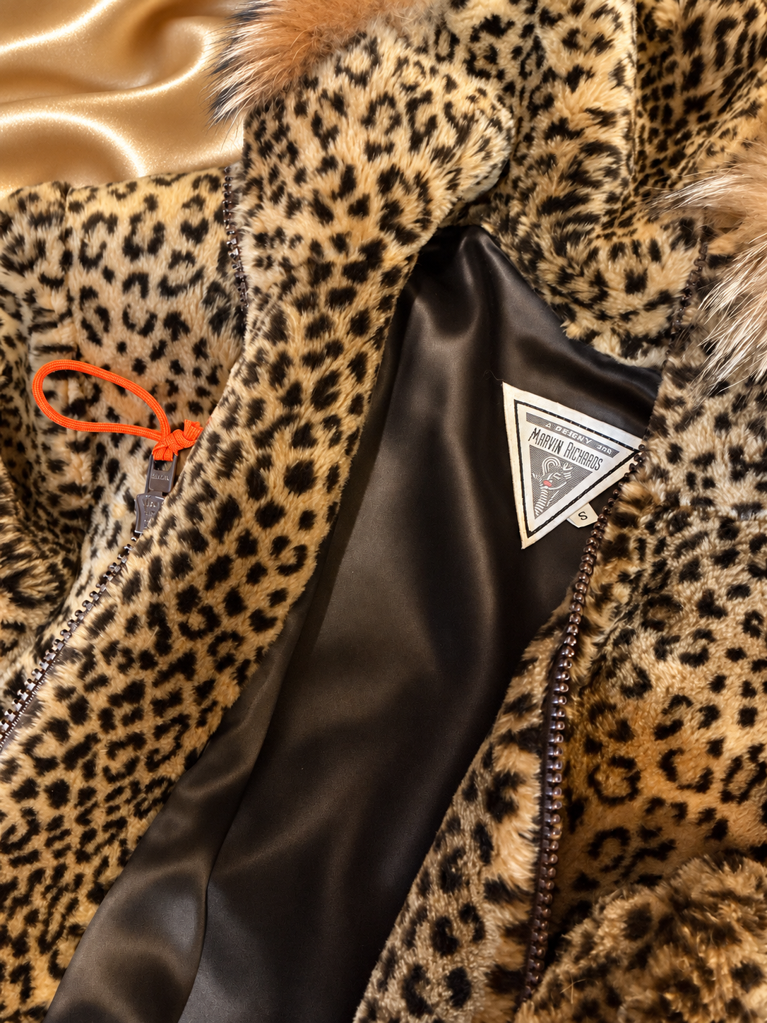 Orange zipper pull and brown lining of leopard jacket on golden satin